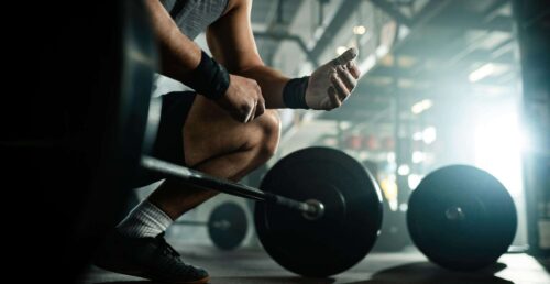 low-angle-view-unrecognizable-muscular-build-man-preparing-lifting-barbell-health-club